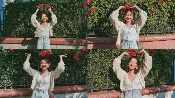 全身肖像：一位美丽的年轻东亚女性，面露灿烂笑容、露出牙齿，涂着红色口红，棕色头发上架着一副太阳镜，佩戴金色镂空花朵耳环与精致珍珠项链；双臂高举，掌心向上，轻柔托住悬于她头顶正上方的一簇红色凌霄花；身着米白色短款针织开衫，内搭同色系白色蕾丝抽绳上衣，浅洗水蓝色高腰直筒牛仔裤，斜挎一只色彩缤纷的小型格纹编织包；站立于低矮的红色花岗岩墙前，墙后为覆满浓密绿色常春藤叶片与红色凌霄花的黑色锻铁围栏；晴朗明媚的夏日，自然柔和的侧向阳光，墙上投下斑驳的树影，洋溢清新治愈的日常氛围；使用 sony a7m4 拍摄，50mm f/1.8 镜头，浅景深，背景虚化柔和，肌肤自然透亮，高清晰度，照片级写实风格。避免 ai 美女脸、低质量、模糊、扭曲、多余肢体、多余手指、畸形特征、过度、不足、噪点、粗糙皮肤、肤色暗沉、表情僵硬、过度平滑、塑料质感、水印、文字、边框、过度精修、塑料皮肤、暗沉肤色、明显痘印、明显皱纹、斑点、面部变形。