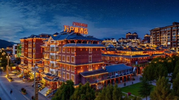 苗侗风格与现代融合，夜景，万户寨酒店招牌，屋檐轮廓灯，绿树成荫，云彩天空，对称构图，暖色调，长曝光，广角镜头，低角度，霓虹光晕，木质结构，石板路，行人剪影，宁静氛围，民族纹样，灯笼点缀，星空背景，微光反射，建筑细节，民族与现代结合。