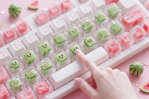 一个超现实风格的键盘，画面展示一整个键盘，每个按键都是方形的冰块，有些冰块里完全包裹着完整的未切开的绿色方形小西瓜，按键上印着小的可爱笑脸，有些包裹着方形的红粉拼接的西瓜果肉，冰块上水珠滑落晶莹剔透的。键盘旁有散落的小西瓜和水珠童趣，乐趣，可爱。键盘上的字母要保留 整体有冰透的感觉 以粉白色调为主，一只白皙纤细的女人手指，用食指轻轻的按键盘，按了一下键盘，键盘弹性十足，